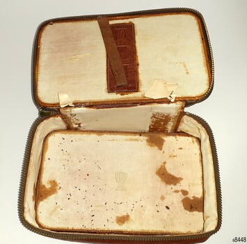 Tan coloured leather pouch with zipper. Straps inside the lid.