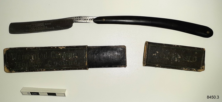 Black case with lid, and black handled razor with steel blade