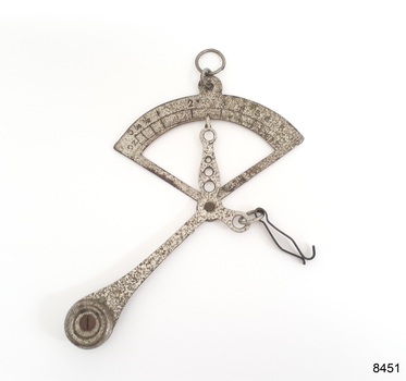Small metal scale has a fixed weight, an indicator pointer and a clip for holding a small item