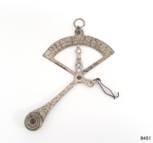 Small metal scale has a fixed weight, an indicator pointer and a clip for holding a small item
