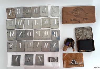 The set comprises metal and paper stencils, a stencil clip, brushes, ink powder and tube, and a mixing lid