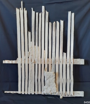 Blond wooden upright slats attached to timber horizontal rails, mortar between some of the slats