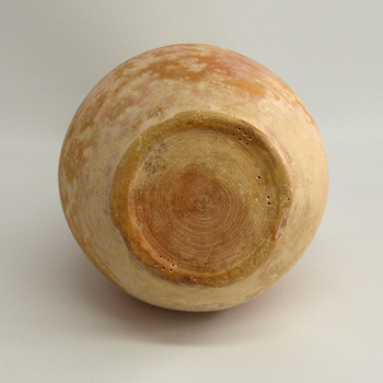 Round base has uneven edges, concentric circles and pinhole marks in a pattern