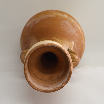 Wide mouth reduces in size. Curved handles are fixed on the neck below the mouth and above the base