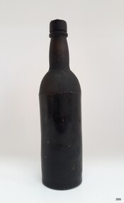 Black glass bottle is tall. The glass has imprefections.