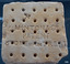 Base of tile, white ceramic surface with five rows of five holes in the base