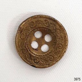 Four holed metal button with decorative border around edge and around holes
