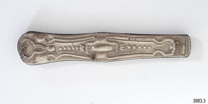 Side of metal pocket knife has impressed fancy design