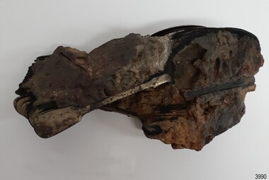 Concretion of matter with handles of metal spoons visible