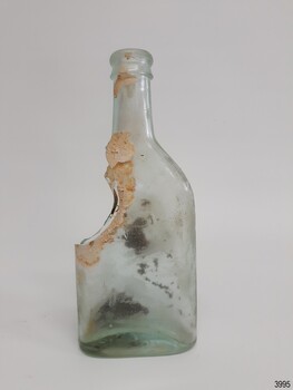 Clear glass rectangular body bottle with one shoulder broken away