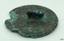 Metal disc, rough, irregular circle, raised area in centre of back containing small hole.