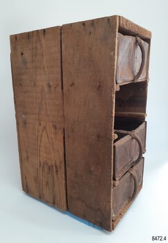 Side of drawer frame has two panels of wood. Drawers' metal handles are vertical  
