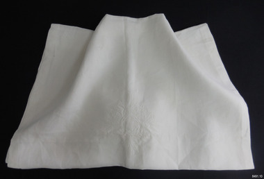 Long rectangle of white cotton cloth with embroidered emblem in centre