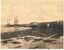 Sepia photograph of the Warrnambool Breakwater showing docked vessels, small buildings and the beach.