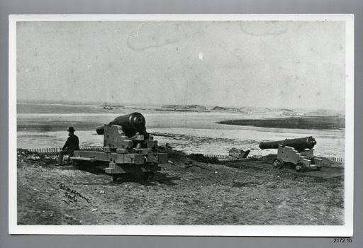 Black and white copy of 2172.1, man seated on one of two cannon carriages overlooking Lady Bay