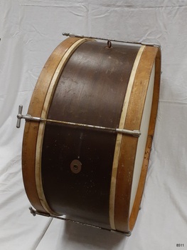 Marching bass drum with metal tension rods and wooden drumheads and shell. Maker's plate attached to shell.