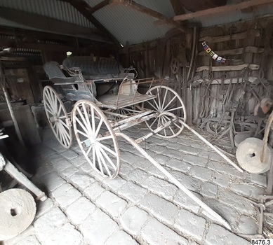 Wooden carriage, four wheels, front bench seat and rear benches along the sides. Leather upholstery.