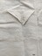 Small square apron pocket with a labelled, buttoned, triangular flap. 