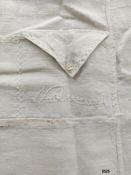 Small square apron pocket with a labelled, buttoned, triangular flap. 