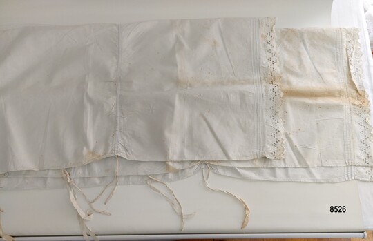 A cotton bolster sham with drawstrings and lace edging.