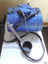 Blue canteen with lid sitting horizontally on a bench and blue copper ladle in front