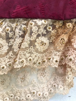 Close up view of bodice lace showing gold coloured beads in flower centres.