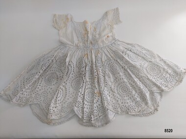 Front view of a white child's dress embroidered with broderie anglaise