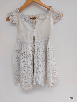 Back view of a white child's dress embroidered with broderie anglaise