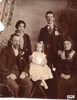 Photograph of Alice Towns (with her family) wearing a white dress embroidered with broderie anglaise