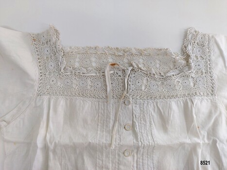 Neckline with hand-crocheted lace and embroidery, buttons and pintucks