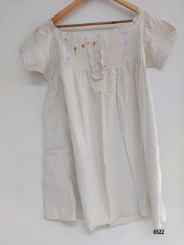 Front view of white, cotton chemise with pintucks and broderie anglaise on front bodice, neckline and sleeves