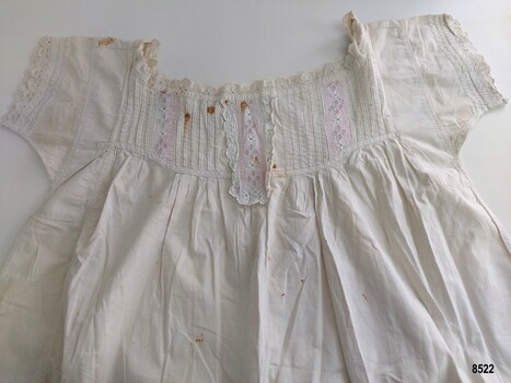 View of front bodice with broderie anglaise trim over pink lining, pintucks and gathered yoke.