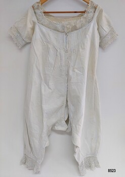 Front view of lady's white, late 19th century combinations. They have short sleeves and are decorated with pintucks and crocheted lace trim.
