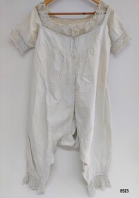 Front view of lady's white, late 19th century combinations. They have short sleeves and are decorated with pintucks and crocheted lace trim.