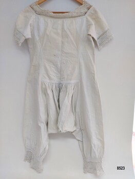 Back view of lady's white, late 19th century combinations. They have short sleeves and are decorated with crocheted lace trim.