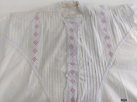 The large triangular yoke of the nightgown is decorated with pintucks and broderie anglaise lace lined with pink ribbon