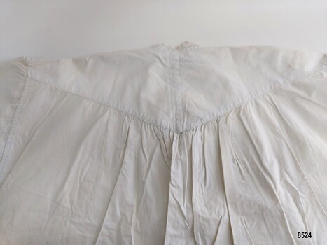 White cotton fabric is gathered onto a triangular yoke
