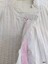 The front placket of the nightgown showing one button and the broderie anglaise lace lined with pink ribbon and bordered with pintucks