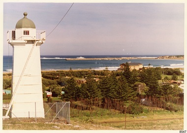 Lower lighthouse in foreground, Surfside Holiday Park and Surf Lifesaving Club in centre, Lady Bay and Breakwater in distance.