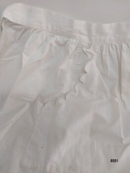 Pocket on right side of apron featuring a scalloped trim along the edge.