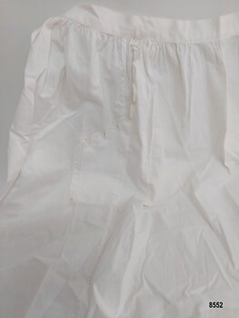 White cotton apron with side pocket featuring a scalloped edge