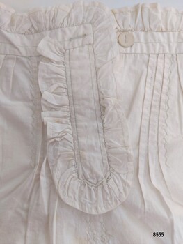 Top right of sampler showing frilled opening, pintucks, decorative embroidery and buttonhole