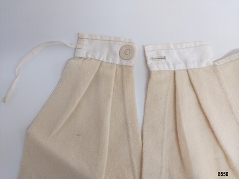 Section of sampler showing pleated opening (placket) with button and buttonhole and tie
