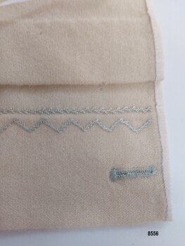 Handstitched tuck, embroidery, binding and buttonhole on bottom corner of sampler