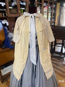 Front view of knee length cape with shorter lace edged top cape and collar.