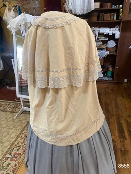 Back view of knee length cape with shorter lace edged top cape and collar.