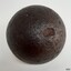 Round black ball with shiny surface that has pits and chips