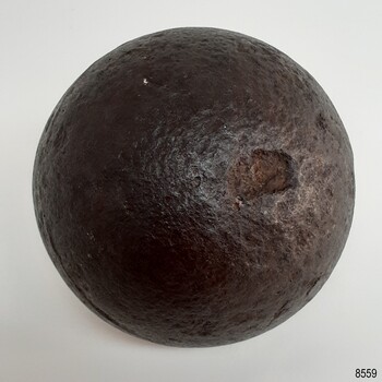 Round black ball with shiny surface that has pits and chips
