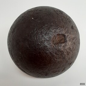 Round black ball with shiny surface that has pits and chips