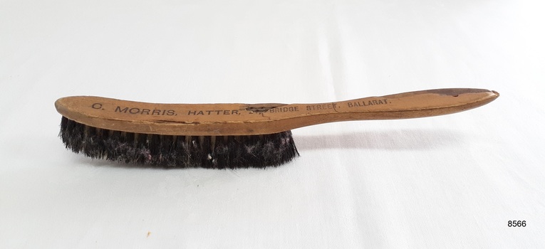 Angled top view of hat brush showing inscription of supplier.
